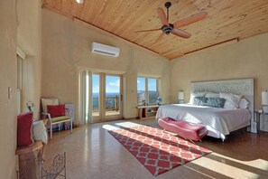 A spacious bedroom with a large bed, a ceiling fan, and a view through the glass doors. - Casa Artista I Romantic, Pool, Hot tub, Endless Views (Wimberley)