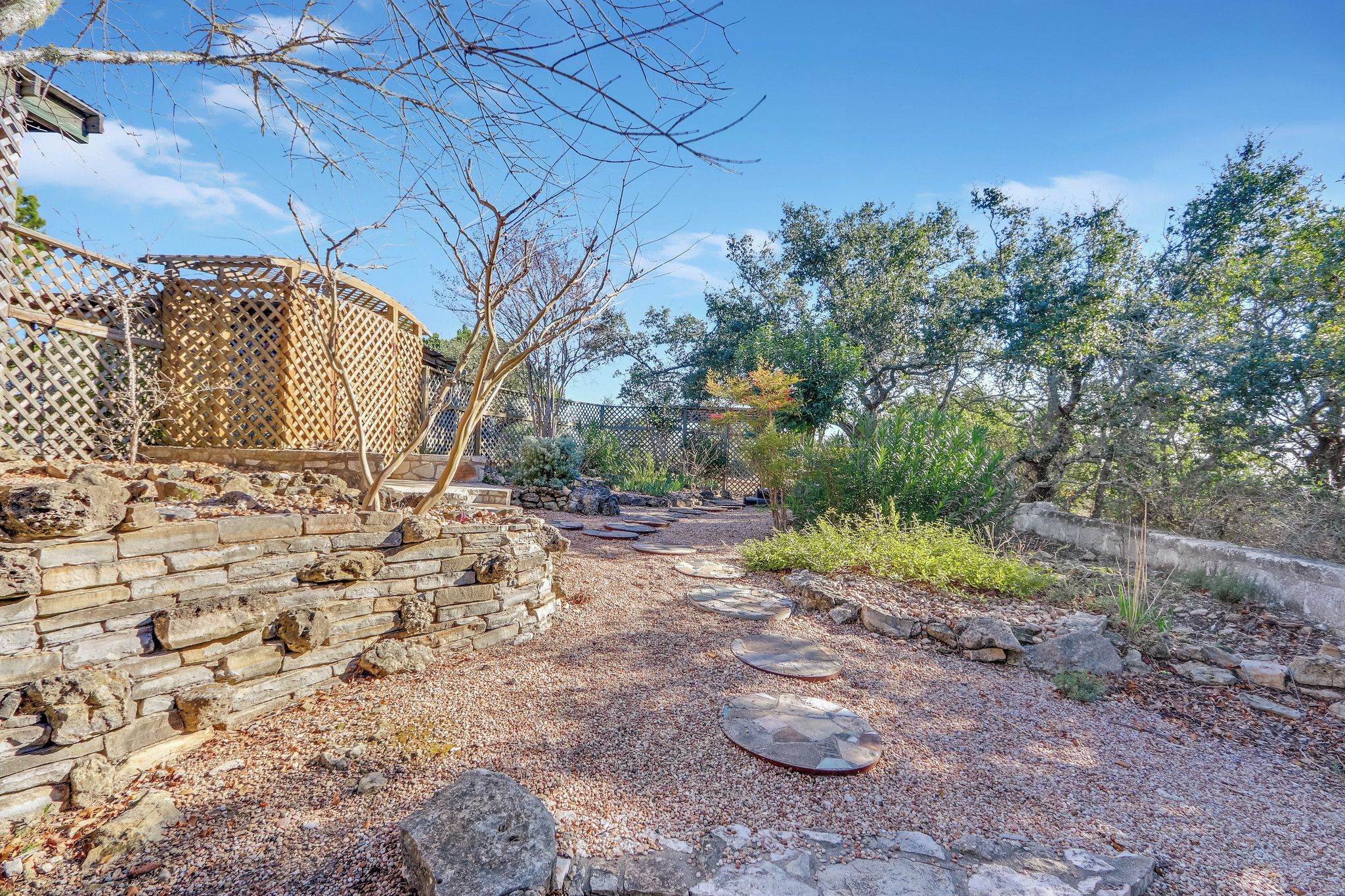 Un sendero en el jardín con escalones de piedra y una valla de madera.