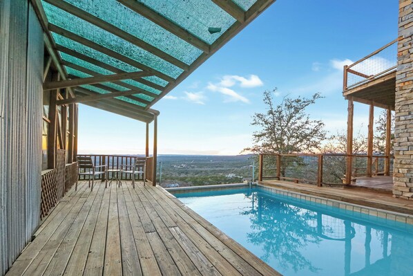 Una terraza de madera con piscina, con vistas a un paisaje pintoresco.