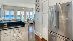 Una cocina moderna con un refrigerador Viking de acero inoxidable, armarios blancos y una isla grande con encimera negra.