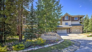 A two-story house with a stone driveway and a sign that reads "Riverbend."