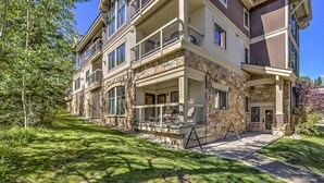 A multi-story building with balconies, stone facade, and a well-maintained lawn.