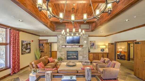 A spacious living room with a stone fireplace, leather sofas, and a wooden ceiling.