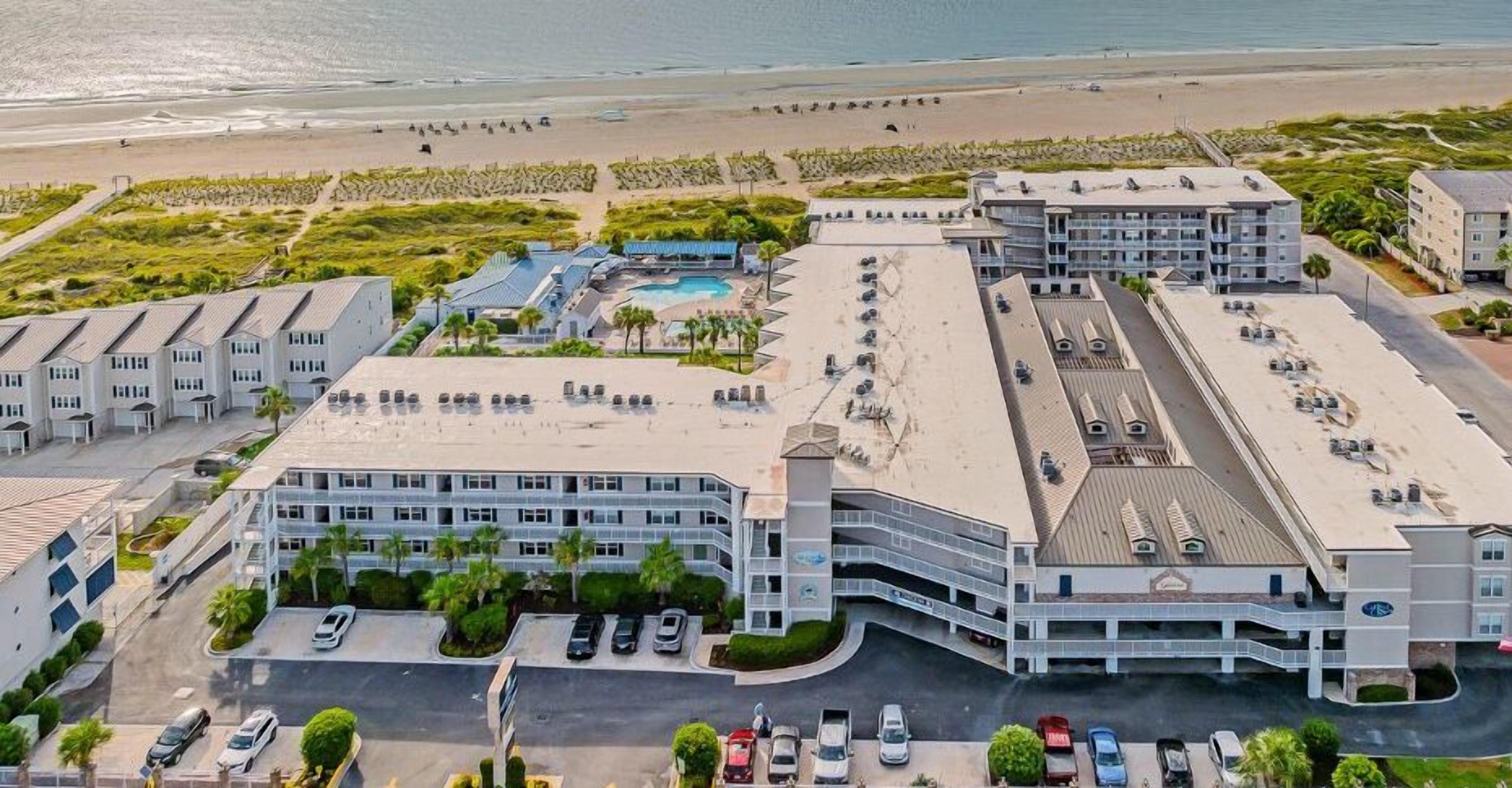 Een hotel met meerdere gebouwen, een zwembad en een strand op de achtergrond.