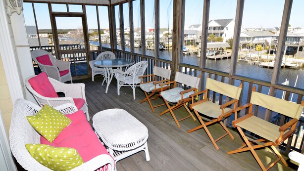 A covered outdoor area with wicker furniture, a round table, and chairs.