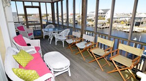 A covered outdoor area with wicker furniture, a round table, and chairs. - Beach Ball - A "Sound" Choice on the Canals (Surf City)