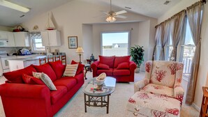 A living room with red sofas, a glass coffee table, and a view of the outside.