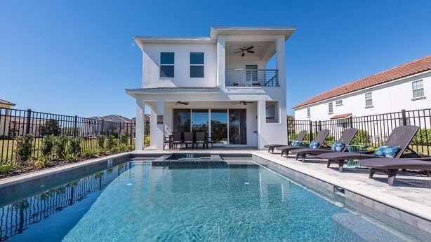 A modern two-story house with a swimming pool, outdoor seating, and a balcony.