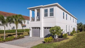 A modern two-story house with a white exterior, a garage, and a paved driveway.