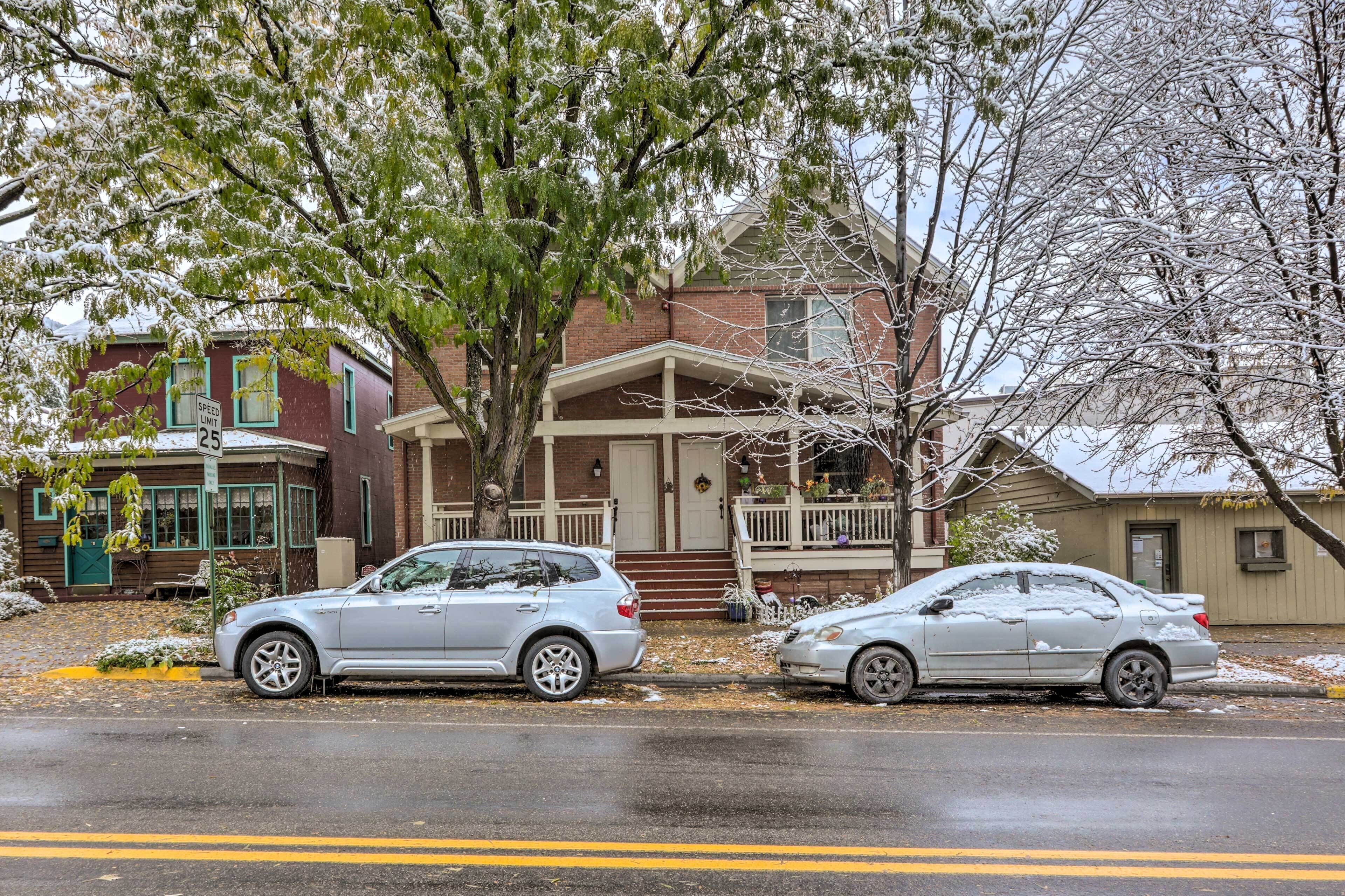Zwei Autos parken in einer Wohnstraße mit Häusern im Hintergrund.