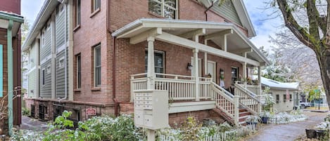A two-story brick house with a covered porch and a small staircase leading to the entrance.