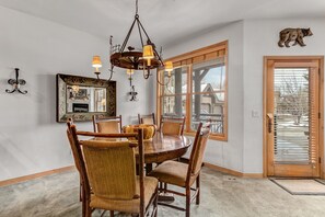 Enjoy meals in this cozy dining area with a round table and six chairs, a large mirror, and a chandelier.
