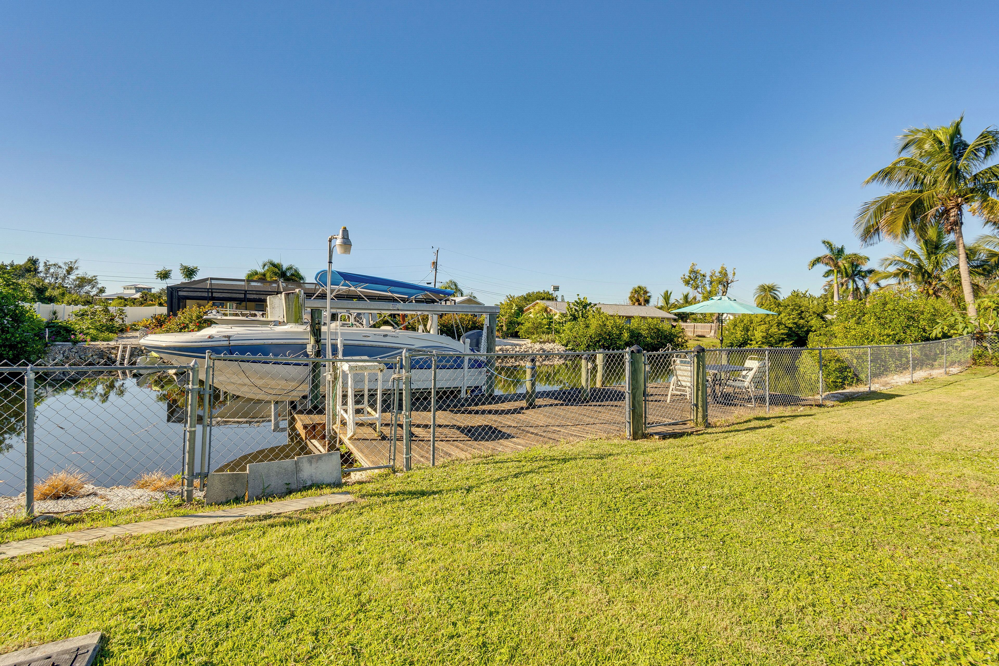 A marina with boats docked, a covered area, and a grassy area with a fence.