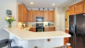 A kitchen with wooden cabinets, a central island, a refrigerator, a microwave, and a sink. - Golf Course View! Group Getaway in Queen Creek (Queen Creek)