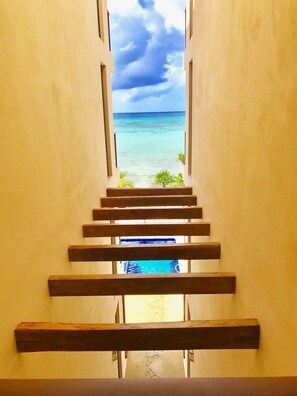 A staircase leading to a beach view with a clear sky.