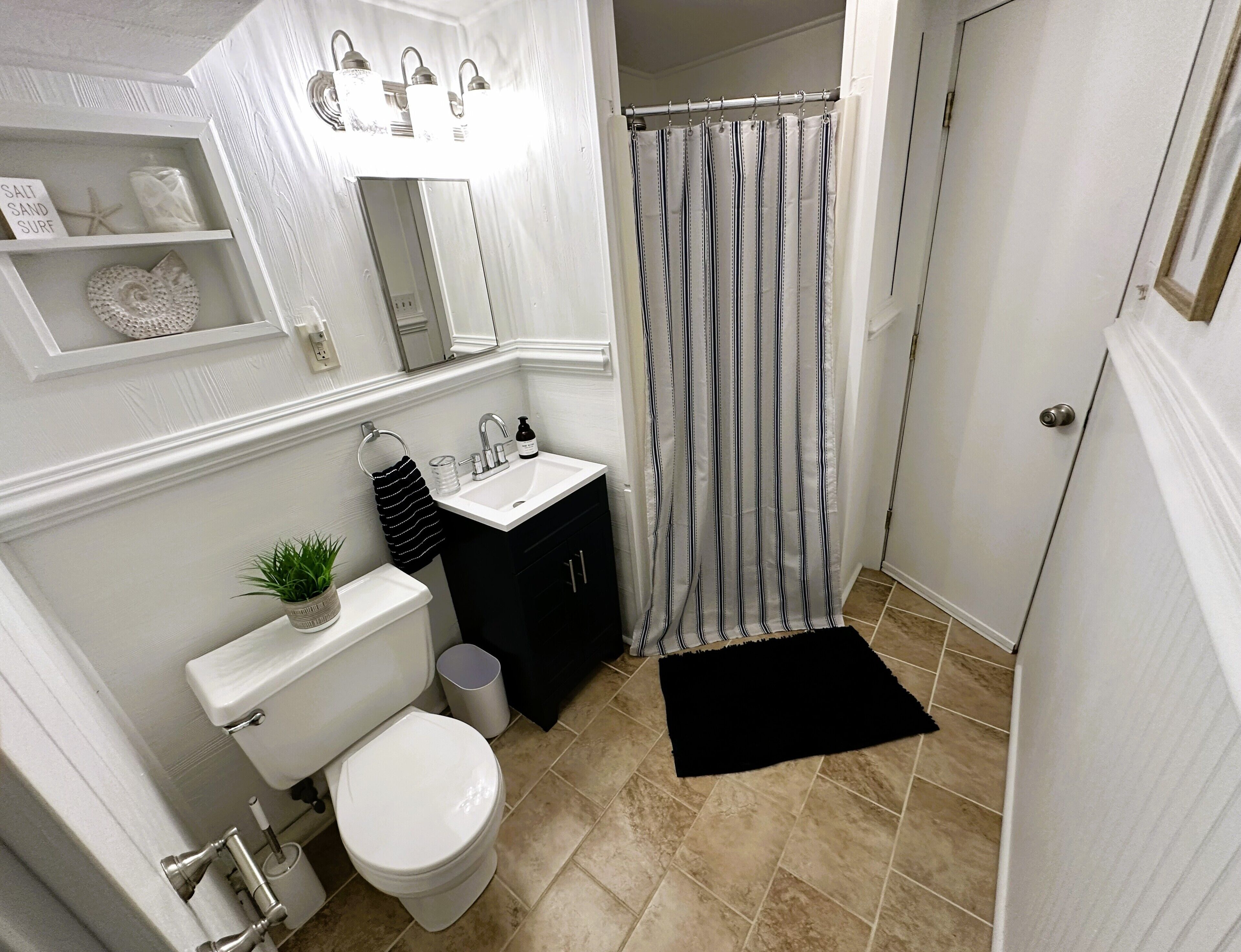Een badkamer met toilet, wastafel, spiegel en douchegordijn.