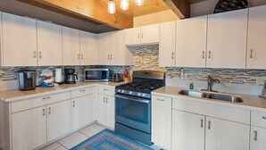 A modern kitchen with white cabinets, a built-in stove, a microwave, and a sink. - Five Pines - Beautifully updated gambrel cabin with Hot Tub and Fenced Yard! (Big Bear Lake)