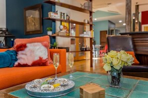 A dining area with a table set for two, featuring a plate of oysters and champagne glasses.