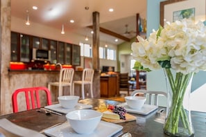 A dining area with a table set for two, white bowls, a plate with cheese and grapes, and a vase with white flowers. - SoCo steps away + screened porch, artsy vibe (Austin)
