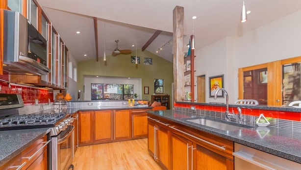 A modern kitchen with wooden cabinets, a stainless steel stove, and a black countertop. - SoCo steps away + screened porch, artsy vibe (Austin)