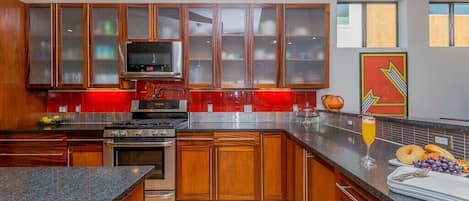 A modern kitchen with wooden cabinets, a stainless steel range, and a red backsplash.