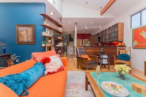 A modern living room with a sofa, coffee table, and a dining area with a table and chairs. - SoCo steps away + screened porch, artsy vibe (Austin)