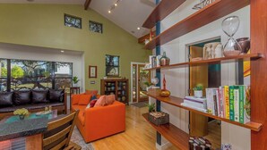 Ein großzügiges Wohnzimmer mit großem Fenster, Kamin, Bücherregal und Essbereich.