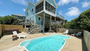 A two-story house with a backyard swimming pool, wooden deck, and outdoor furniture. - OS628- 4 Br. Oceanside with Pool, Hot tub, and Short walk to beach! (Corolla)
