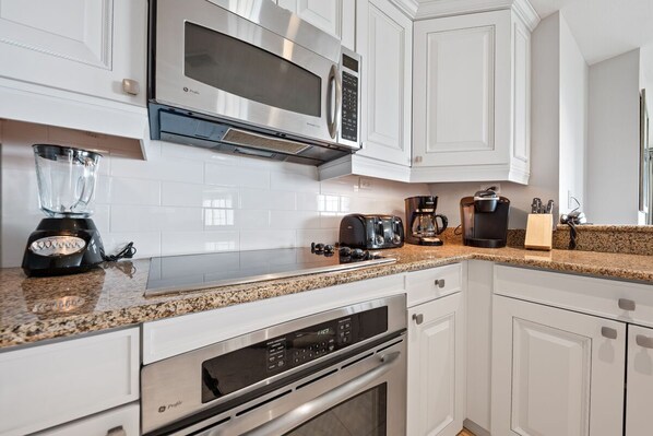 A modern kitchen with white cabinets, stainless steel appliances, a granite countertop, and a built-in oven. - Condo with Two Terrace Balconies with Panoramic Views (Kissimmee)