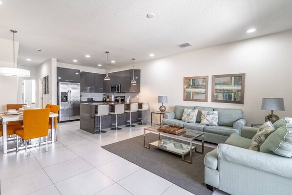 A modern living room with a sofa, coffee table, and dining area with chairs.