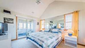 Une chambre à coucher avec un lit, une télévision, un bureau et une fenêtre avec des rideaux.