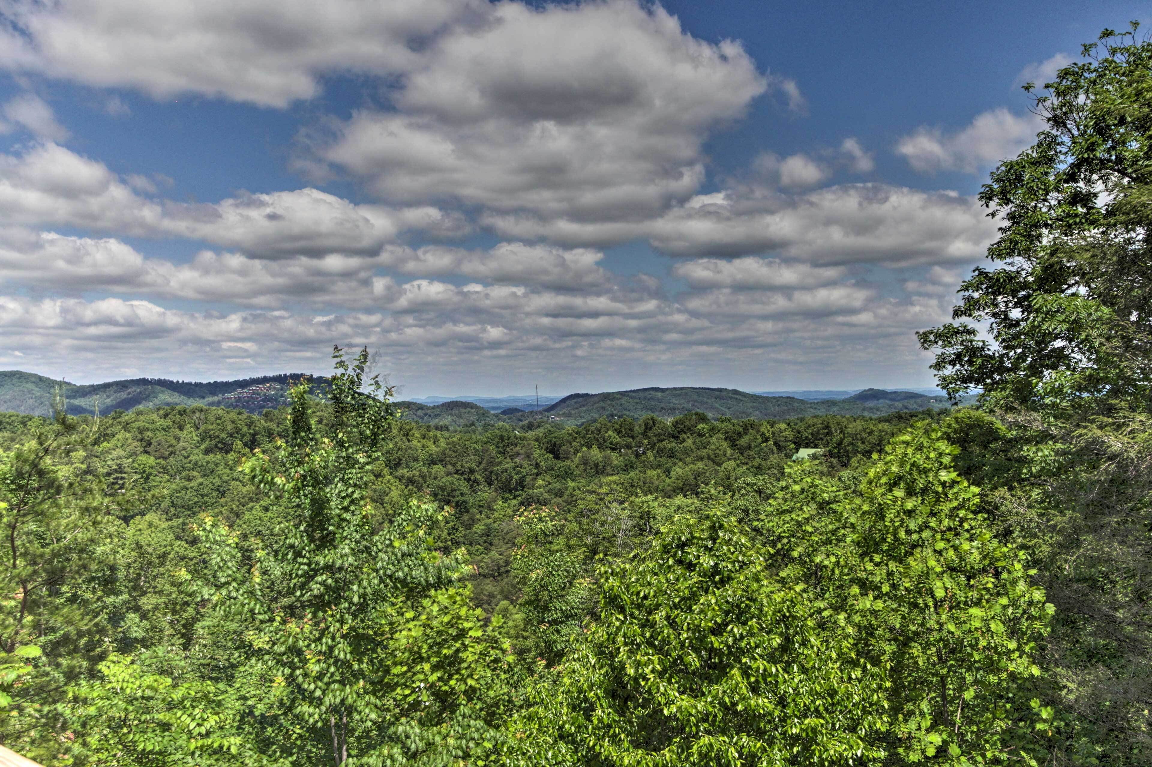 A lush, green landscape with dense foliage and rolling hills under a partly cloudy sky.