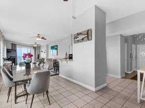 A spacious living area with a large dining table, comfortable seating, and a view of the ocean.