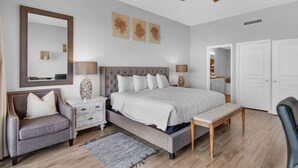 Ein modernes Schlafzimmer mit einem großen Bett, einem Deckenventilator, einem Spiegel und einem Nachttisch mit Lampen.