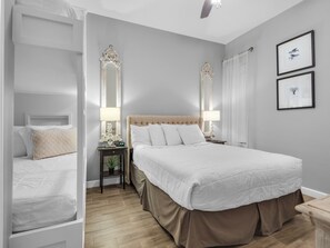 A bedroom with a large bed, two bedside tables with lamps, a mirror, and framed pictures on the wall.