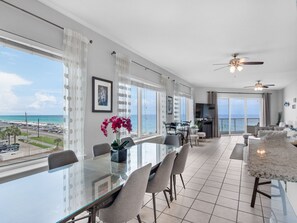 Relax in this spacious living area with a large dining table and chairs, offering a stunning view of the beach and ocean.