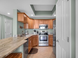 Kitchen features stainless steel appliances, a marble countertop, and wooden cabinetry.