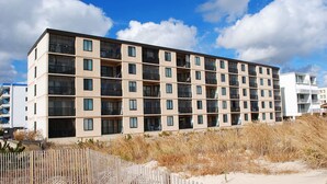 A multi-story hotel with a modern design, featuring balconies on each floor. - Lush, stylish 2 bedroom oceanfront condo with free WiFi, beach decor, and a stunning ocean view located uptown and only a few steps to the beach! (Ocean City)