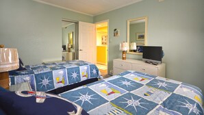 A hotel room with two beds, a television on a dresser, and a door leading to a hallway. - Lush, stylish 2 bedroom oceanfront condo with free WiFi, beach decor, and a stunning ocean view located uptown and only a few steps to the beach! (Ocean City)