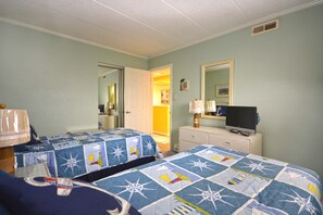 A hotel room with two beds, a television on a dresser, and a door leading to a hallway.