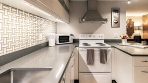 Una cocina moderna con un lavamanos de acero inoxidable, electrodomésticos blancos y un salpicadero con diseño.