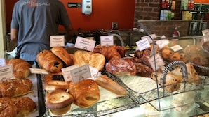 Mostrador de pastelería con diversas opciones de repostería y una persona al fondo.