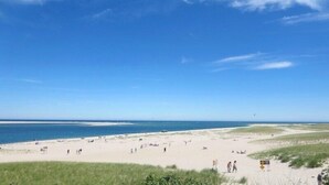 Een breed zandstrand met een helderblauwe lucht en een rustige zee.