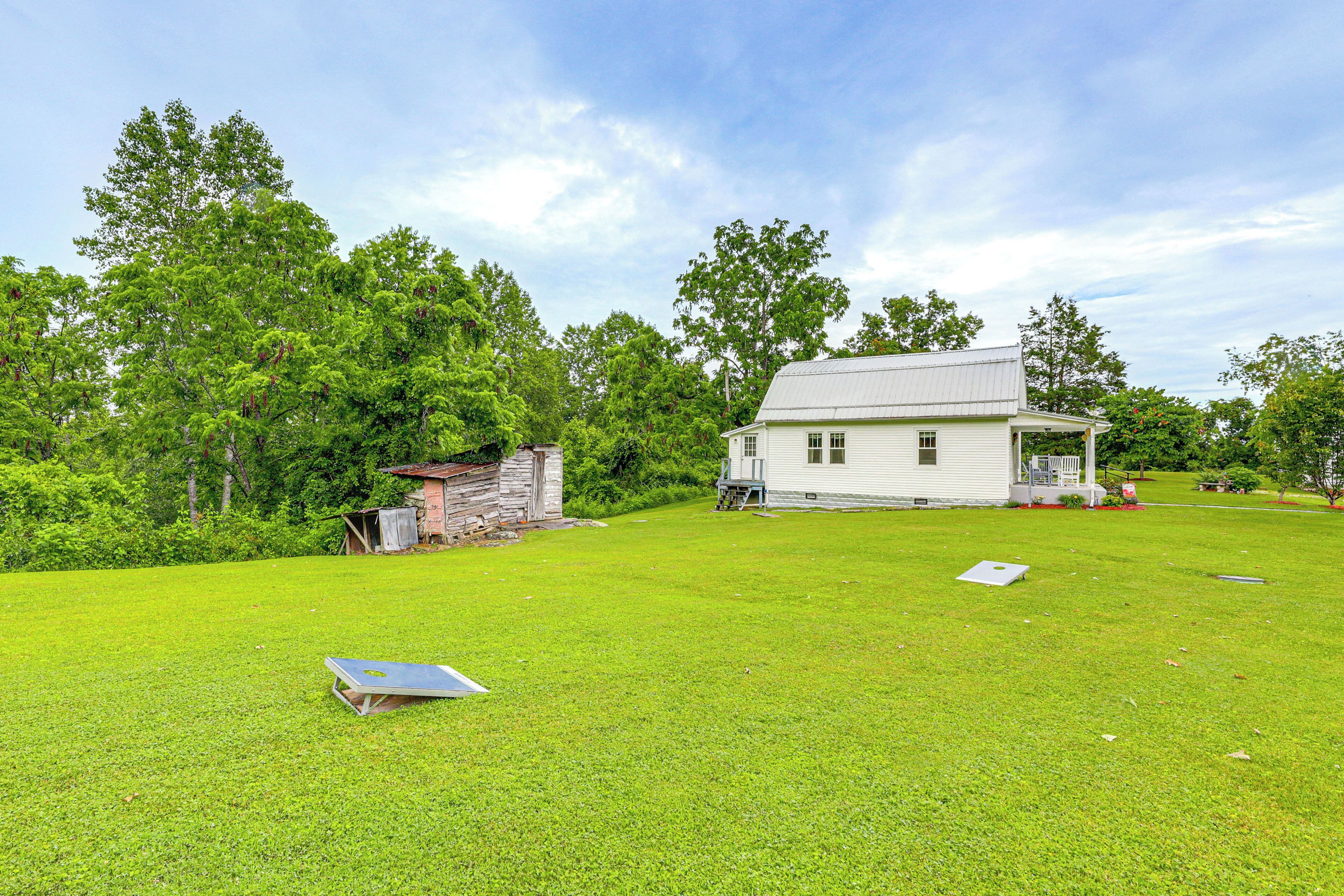 A white house with a porch, surrounded by a grassy yard and trees.