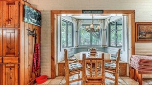 A cabin interior with a wooden dining table, chairs, a bench, a red bowl, and a sign welcoming guests. - Alto Mtn Retreat on 8 Acres w/ Indoor Hot Tub (Alto)