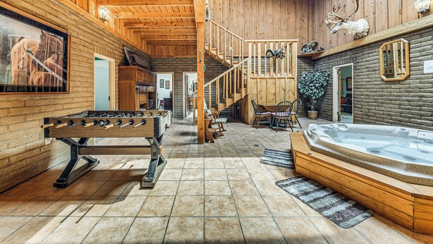 A wooden interior with a foosball table, a hot tub, and a staircase. - Alto Mtn Retreat on 8 Acres w/ Indoor Hot Tub (Alto)