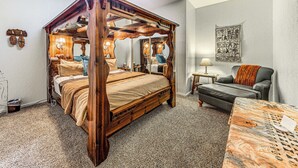 A four-poster bed with a wooden canopy, a gray sofa, a small table with a patterned tablecloth, and a wall tapestry. - Alto Mtn Retreat on 8 Acres w/ Indoor Hot Tub (Alto)