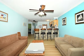 A living room with two sofas, a wooden coffee table, and a ceiling fan.
