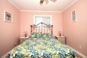 A bedroom with a bed, two nightstands, a window, and a ceiling fan.