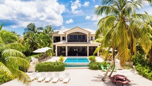 Een resort met een zwembad, ligbedden en palmbomen.